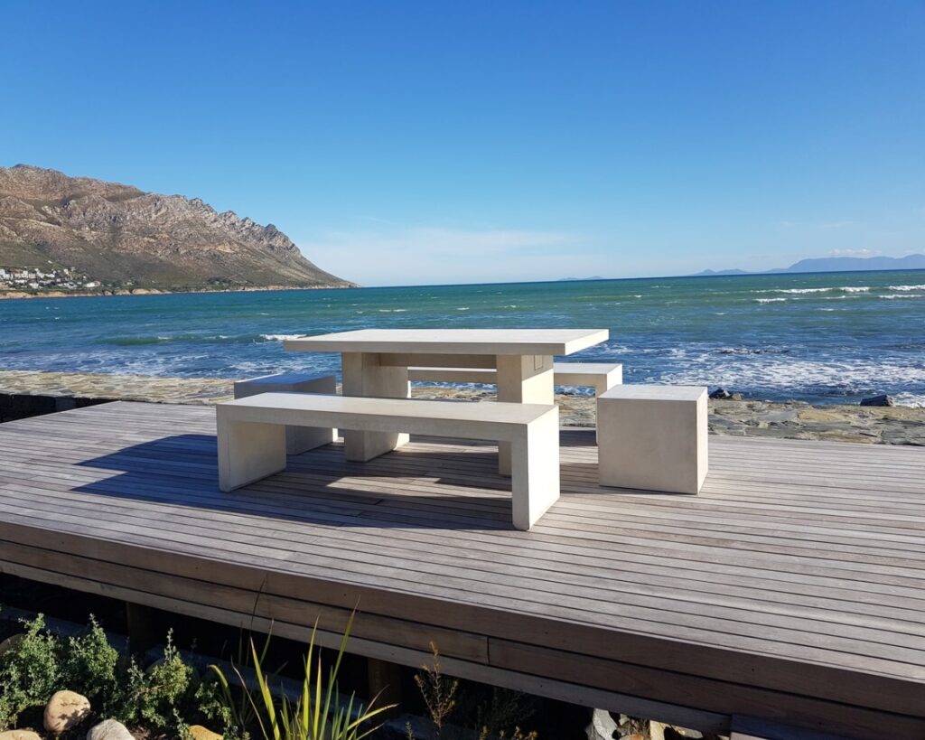 Stonecast Table with forum benches and forum500 seats on a wooden deck by the sea