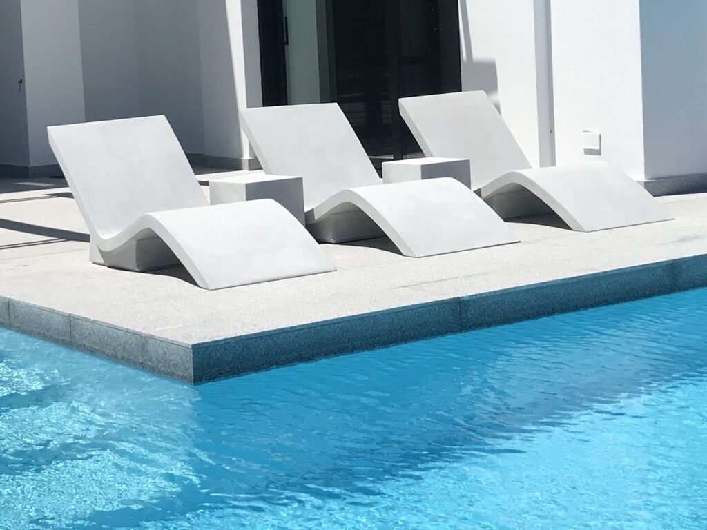 Three Stonecast pool loungers in a row alongside a pool